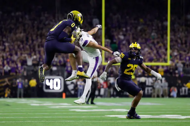 HOUSTON, TEXAS - JANUARY 08: Mike Sainristil #0 of the Michigan Wolverines intercepts a pass intended for Jalen McMillan #11 of the Washington Huskies in the fourth quarter during the 2024 CFP National Championship game at NRG Stadium on January 08, 2024 in Houston, Texas. (Photo by Carmen Mandato/Getty Images)